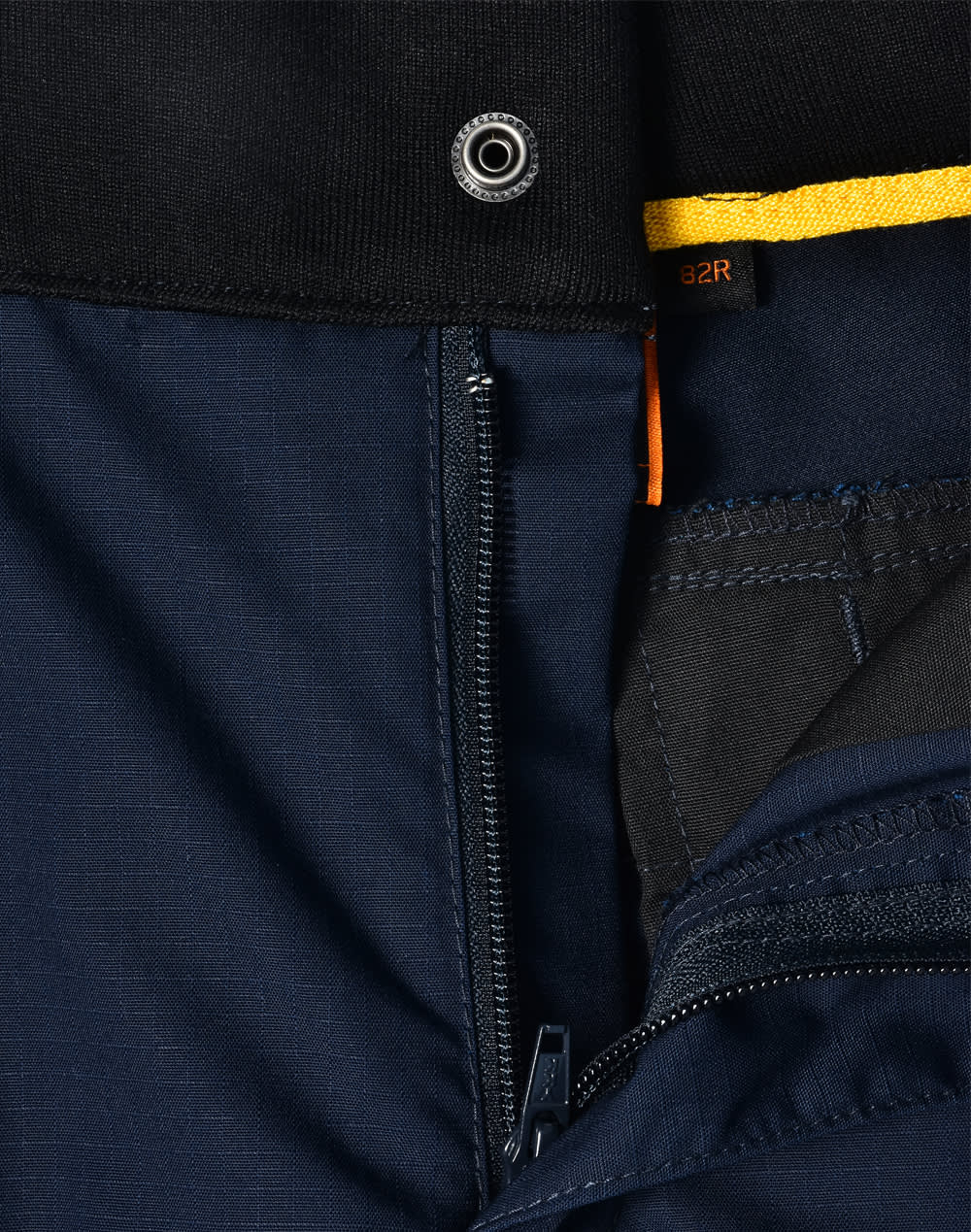 A close-up of navy Rip-Stop Poly/Cotton Stretch Work Pants, showcasing the zipper and fabric texture. Features a logo.