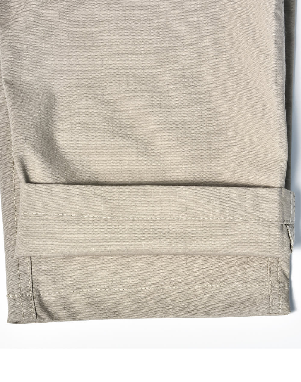 A pair of light khaki Rip-Stop poly/cotton stretch work pants with a cuffed hem. Features a logo.