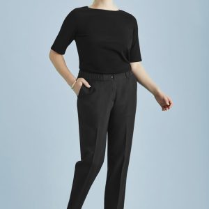 A woman in a black top and black ultra comfort waist pants poses against a light blue background. The pants feature a waistband and pockets.