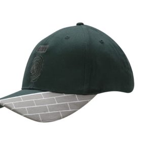 A green cap featuring a fabric insert with a grey brick pattern and embroidered details on the peak.