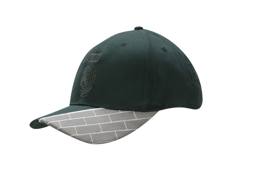 A green cap featuring a fabric insert with a grey brick pattern and embroidered details on the peak.