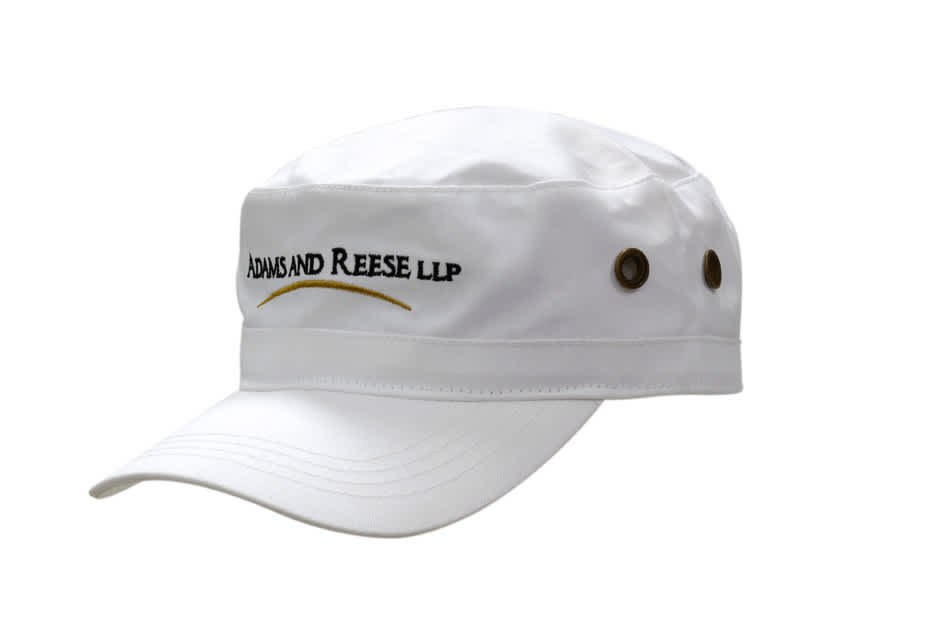 A white military style cap with a stiff brim and side ventilation holes, featuring a logo on the front.