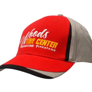 A red and grey cap with fabric inserts on the crown and peak, featuring a logo on the front.