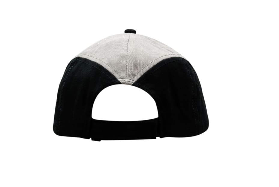 A black and grey cap featuring fabric inserts on the crown and peak, with an adjustable strap at the back.