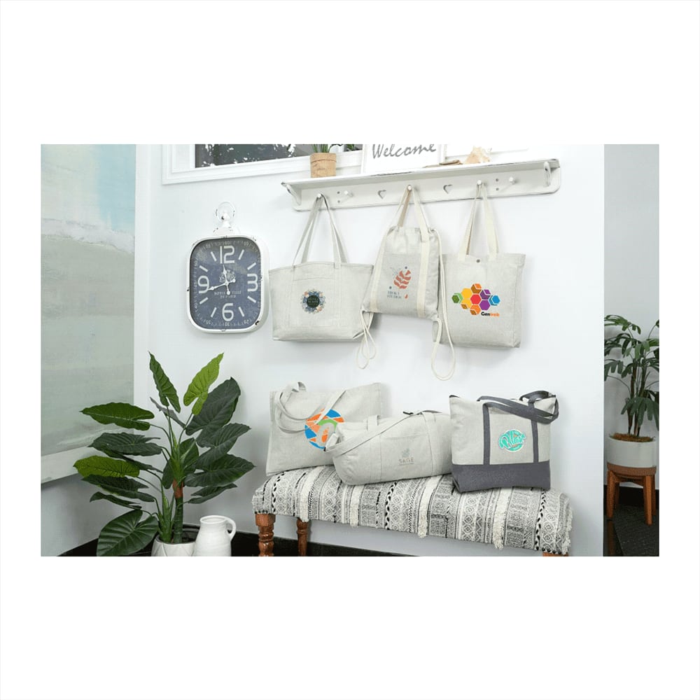 A collection of drawstring bags in grey, featuring different designs and a logo, displayed on a wall and bench.