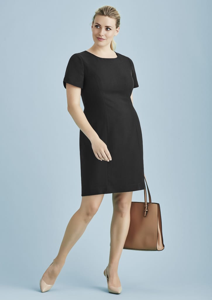 A black short sleeve shift dress paired with a brown handbag, modelled against a light blue background.