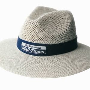 A cream-coloured straw hat with a navy band and a logo, featuring a wide brim and a textured design.