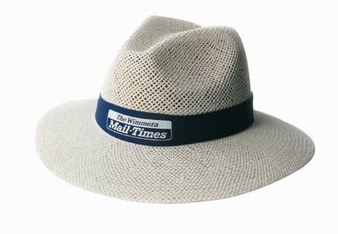 A cream-coloured straw hat with a navy band and a logo, featuring a wide brim and a textured design.