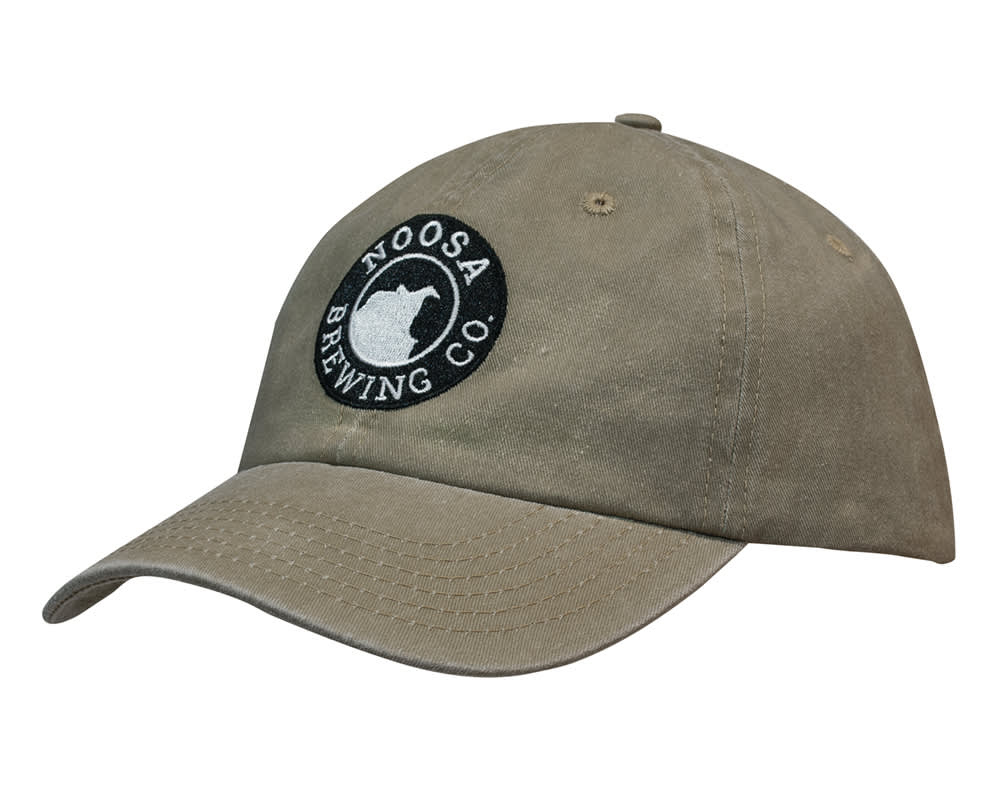 A khaki cap with a curved brim and an embroidered logo. Made from enzyme washed pigment dyed cotton twill.
