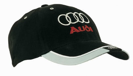 A black brushed heavy cotton cap with reflective trim and tab on the peak, featuring a logo on the front.