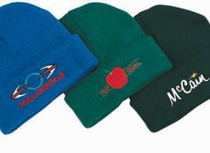 Three acrylic beanies in blue, green, and dark green, featuring various logos on the front.