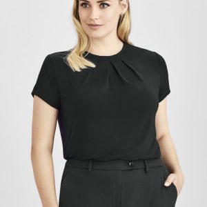 A woman wearing a black short sleeve top with a pleated design, paired with black trousers. The top features a logo.