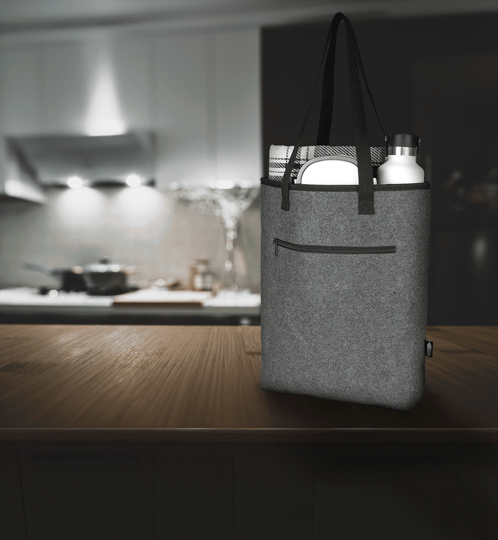 A grey recycled felt cooler tote bag with a zipper pocket, being held by a person wearing casual attire.