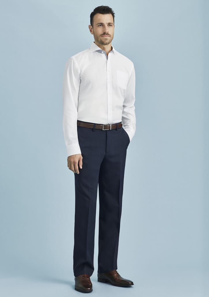 A man wearing a white shirt and navy blue flat front pants, standing against a light blue background.