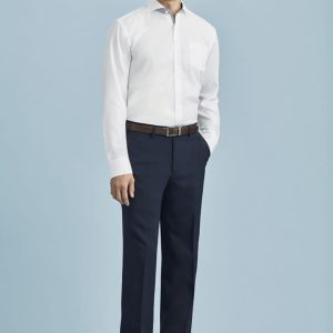 A man stands wearing flat front navy blue slacks paired with a white shirt and brown belt, against a light blue background.