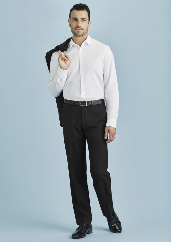 A man in a white shirt and black slacks, holding a jacket over his shoulder against a light blue background.