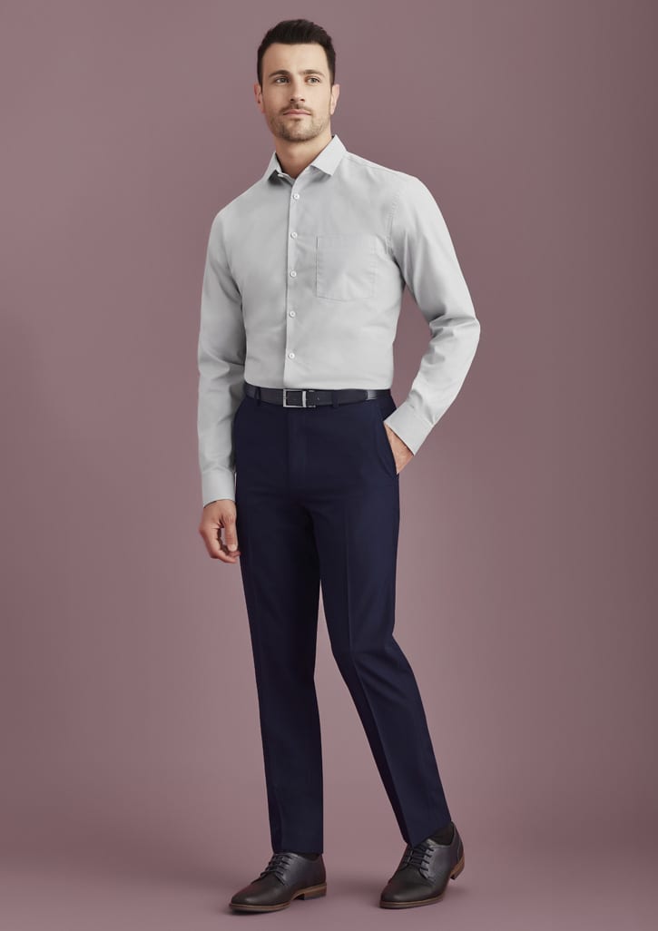 Men's slim fit flat front pants in navy, paired with a light grey shirt and black shoes. Features a logo on the waistband.