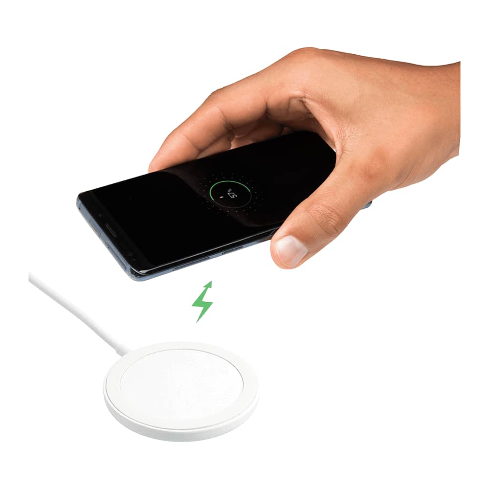 A hand reaching towards a white wireless charging pad with a smartphone above it, indicating charging action.