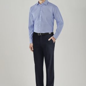 A man in a light blue shirt poses in dark navy adjustable waist slacks, wearing a belt and dress shoes.