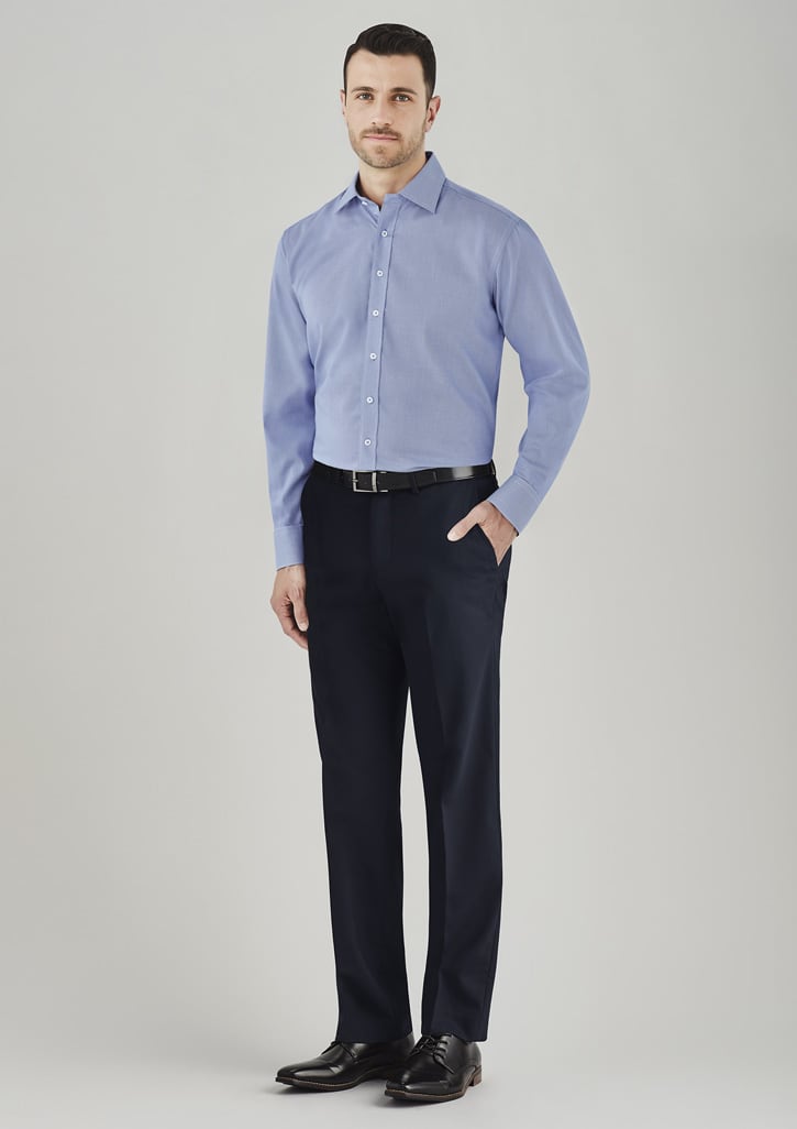 A man in a light blue shirt poses in dark navy adjustable waist slacks, wearing a belt and dress shoes.