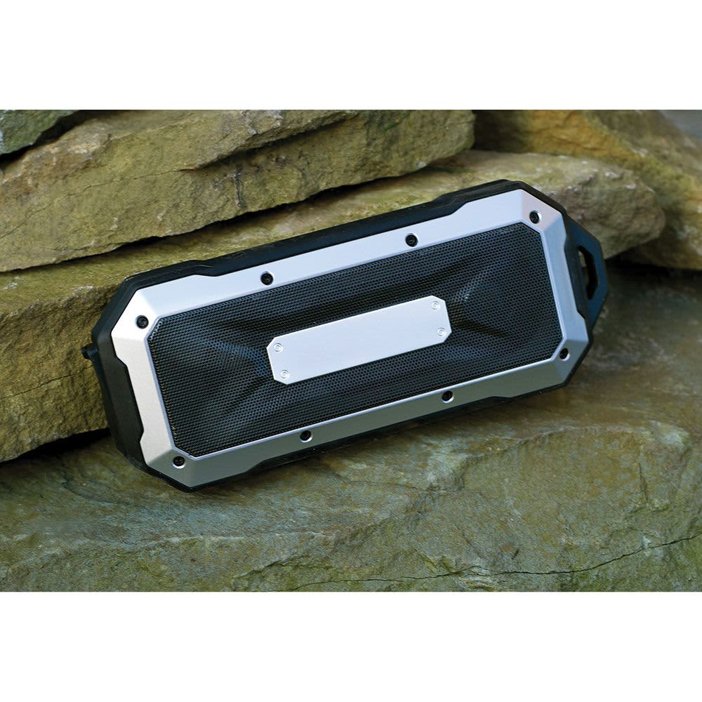 A rugged, waterproof Bluetooth speaker in black and silver, resting on a rock surface.