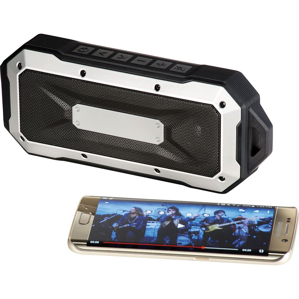 A rugged black and silver Bluetooth speaker beside a smartphone displaying a video. The speaker has a logo on it.
