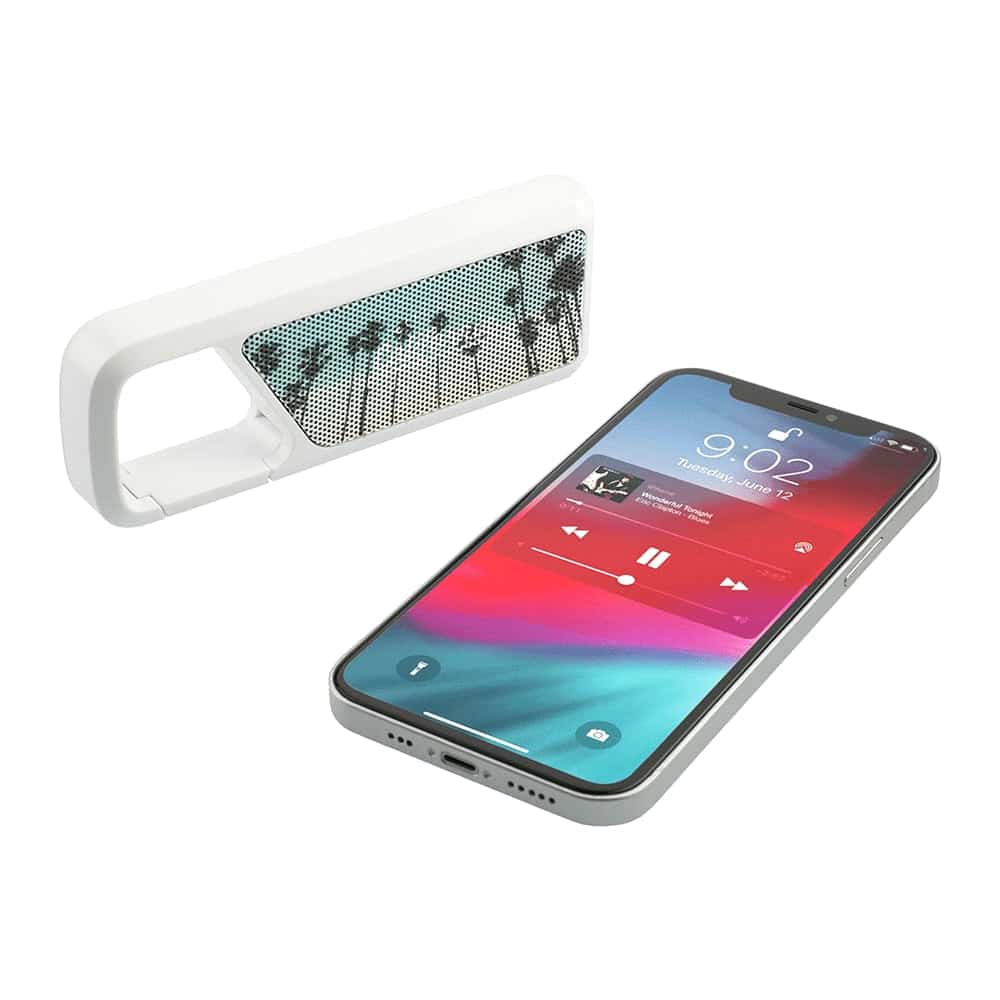 A white Bluetooth speaker with a perforated design beside a smartphone displaying a music app and vibrant screen.