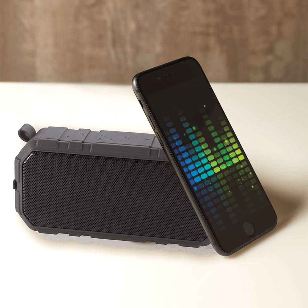 A grey outdoor waterproof Bluetooth speaker placed next to a smartphone displaying a visual equaliser.