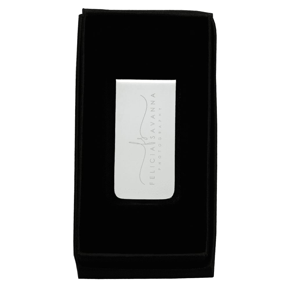 A sleek metal money clip in a black velvet presentation box, with a reflective surface and a subtle logo.