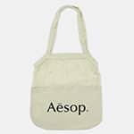 A light cream cotton shopping tote with a logo on the front and two handles.