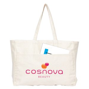 A large cream canvas tote bag with a front pocket and a logo. A sheet of paper is partially visible inside the bag.
