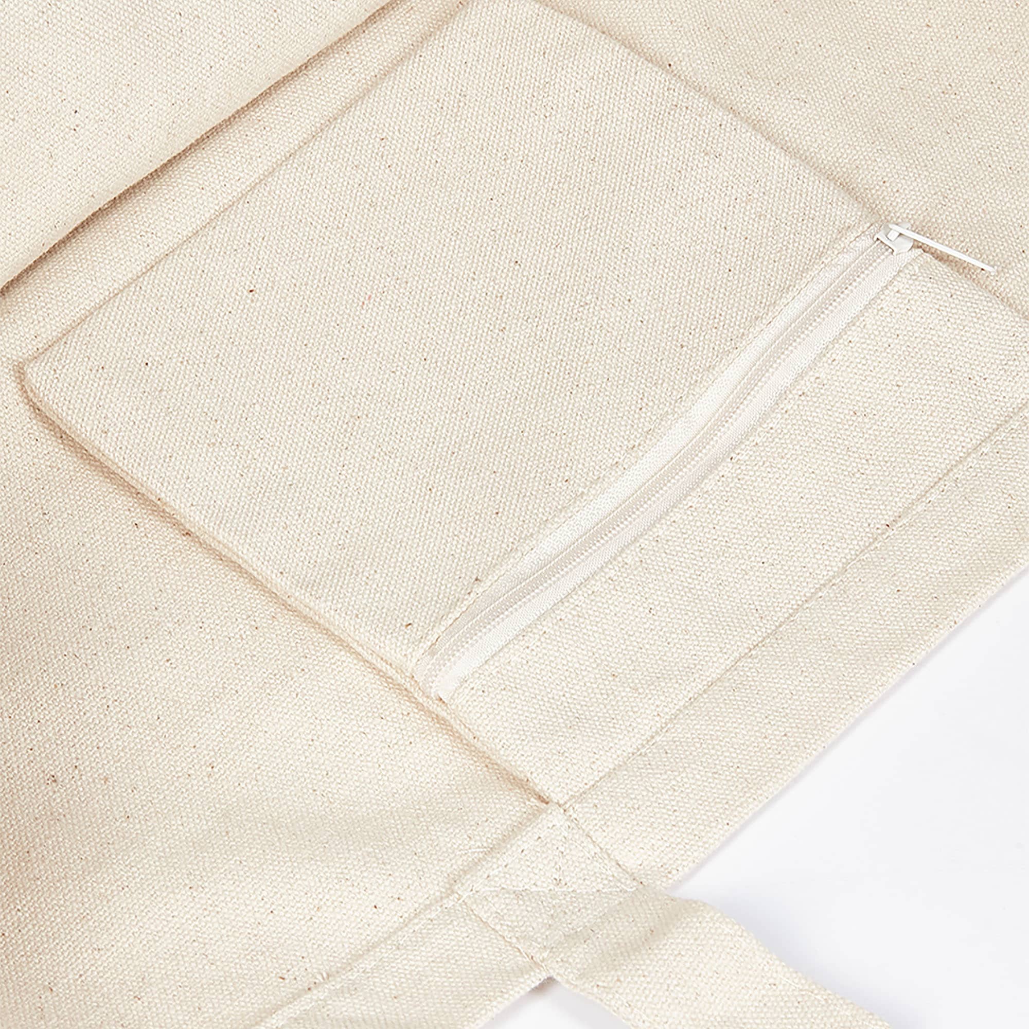 A large, cream-coloured canvas tote bag featuring a zippered pocket on the front and a simple design.