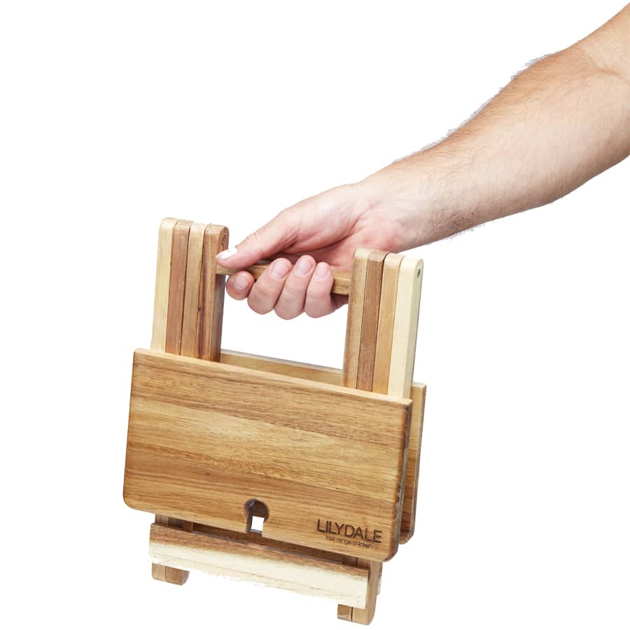 A hand holding a foldable cheese and wine board made of wooden materials in natural tones. The product has a logo.