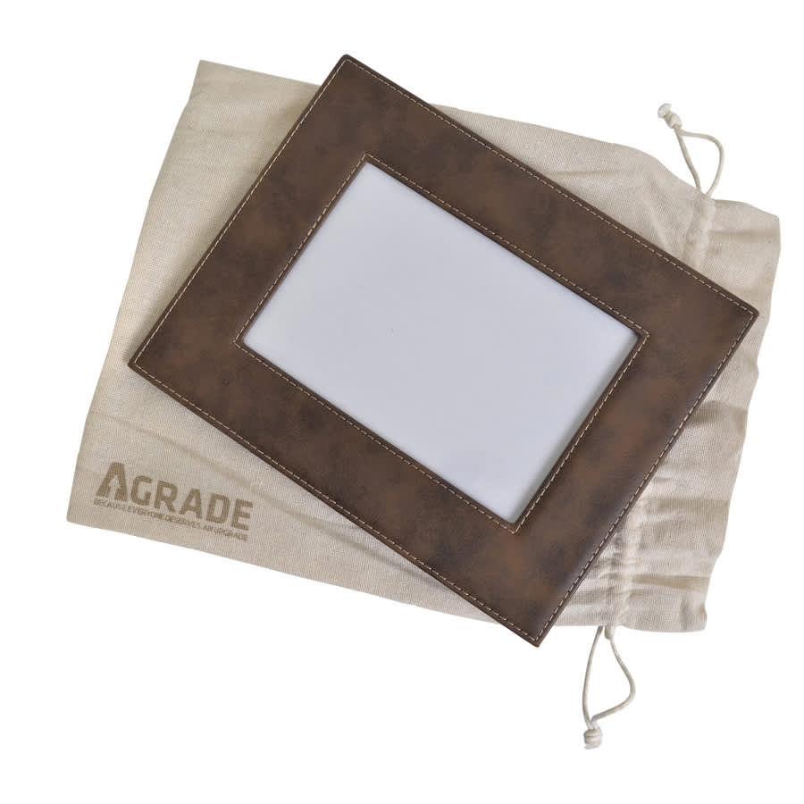 A brown 5x7 photo frame with stitching, resting on a beige drawstring pouch featuring a logo.