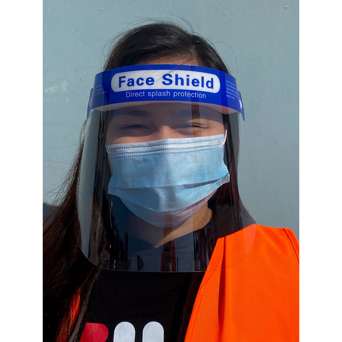 A full-length face shield with a blue band, worn over a surgical mask, accompanied by a bright orange vest.