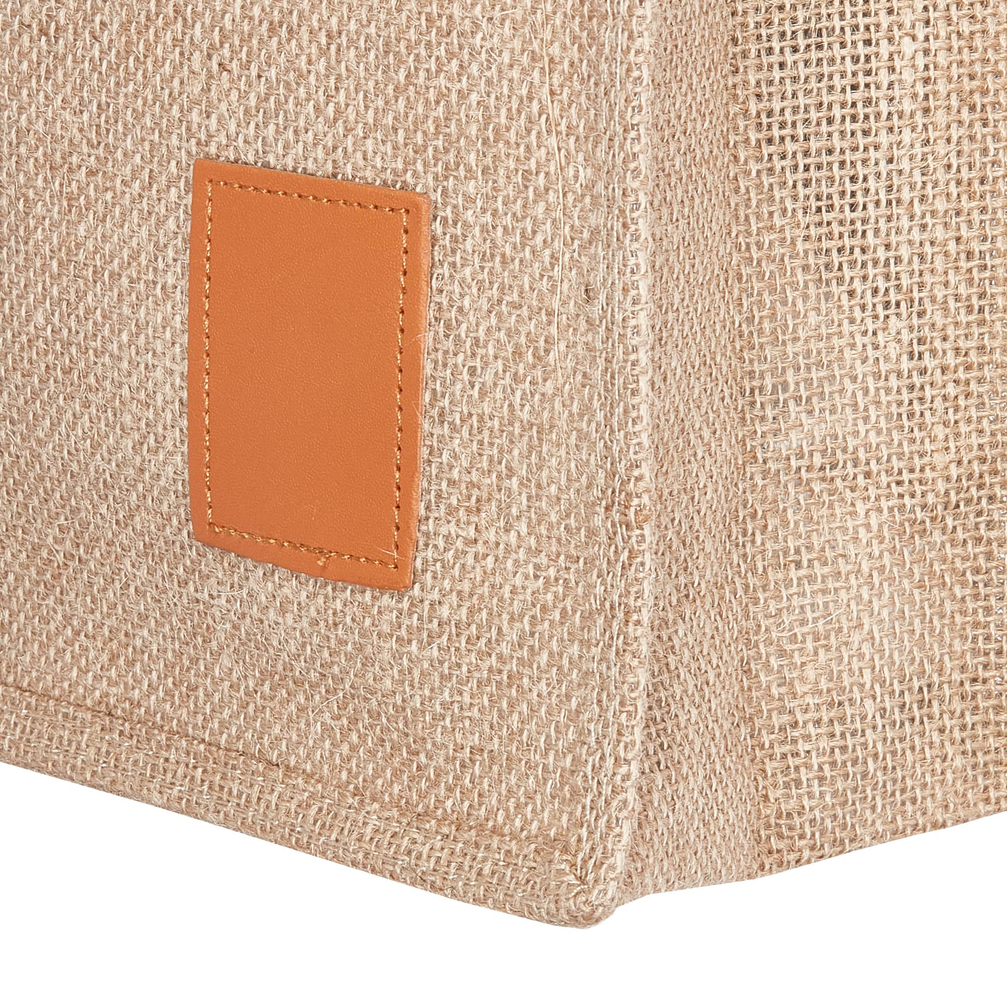 A jute bag in natural brown with a brown leather patch on the side, featuring a textured, woven design.