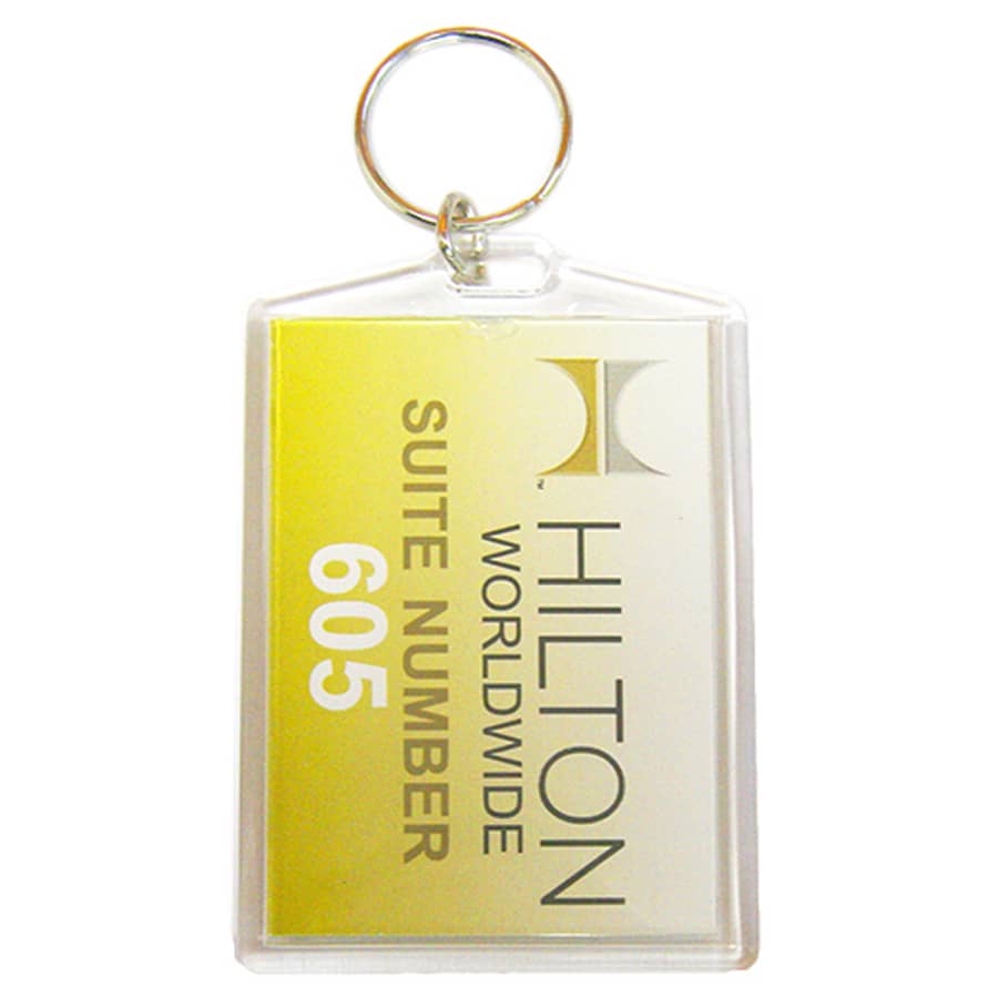 A hotel keychain with a transparent plastic casing, featuring yellow and white colours and a logo.