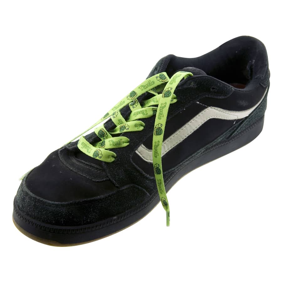 A sneaker with black fabric, featuring bright green laces adorned with a branding logo.