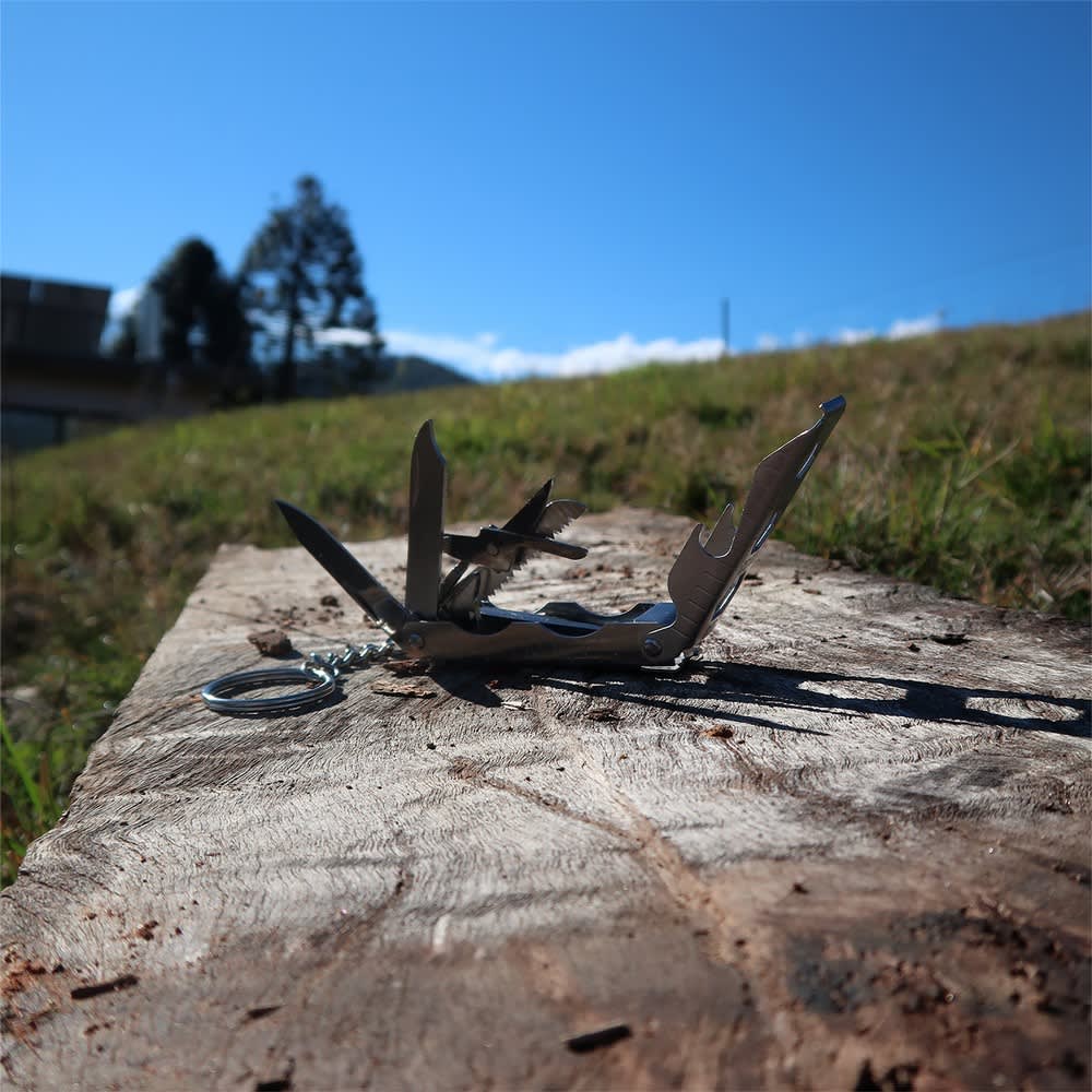 A multi-tool with various tools displayed on a wooden surface, set against a blue sky and grassy background.