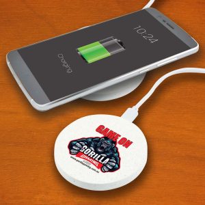 A circular, light-colored wireless charger with a logo, placed beside a smartphone displaying a charging battery icon.