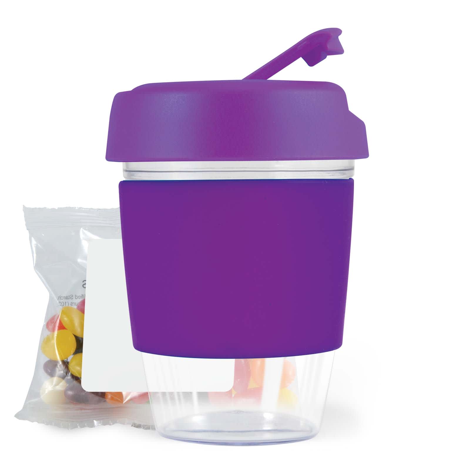 A purple reusable coffee cup with a lid and a clear bottom, accompanied by a pack of jelly beans.