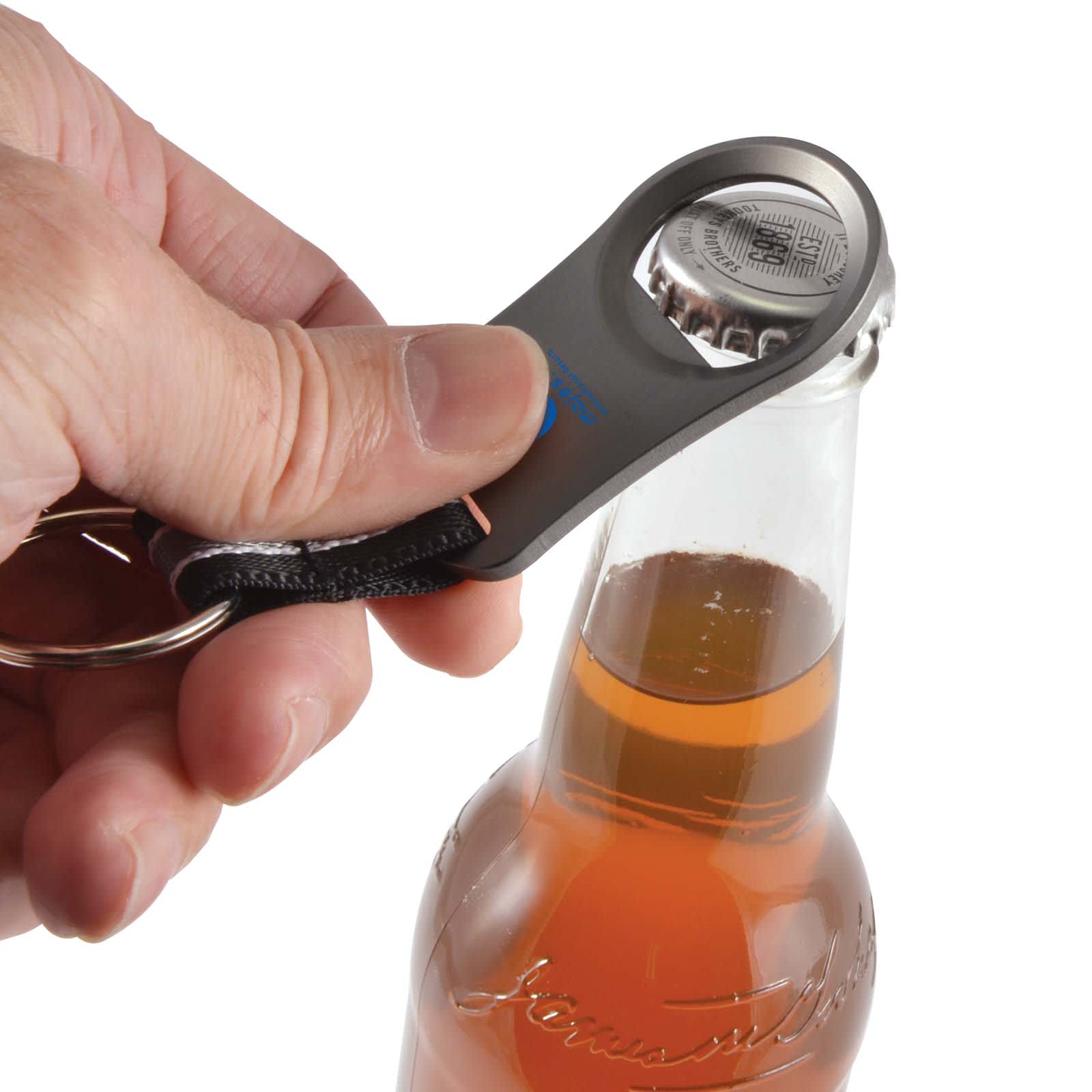 A drink bottle opener in gray is being used to remove a cap from a glass bottle of beverage.