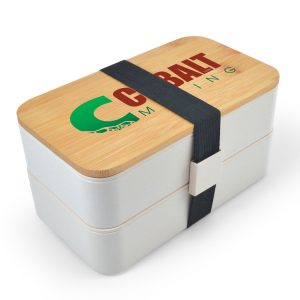 A stackable lunch box in pink with a bamboo lid and utensils, secured by a black strap. It features a logo.