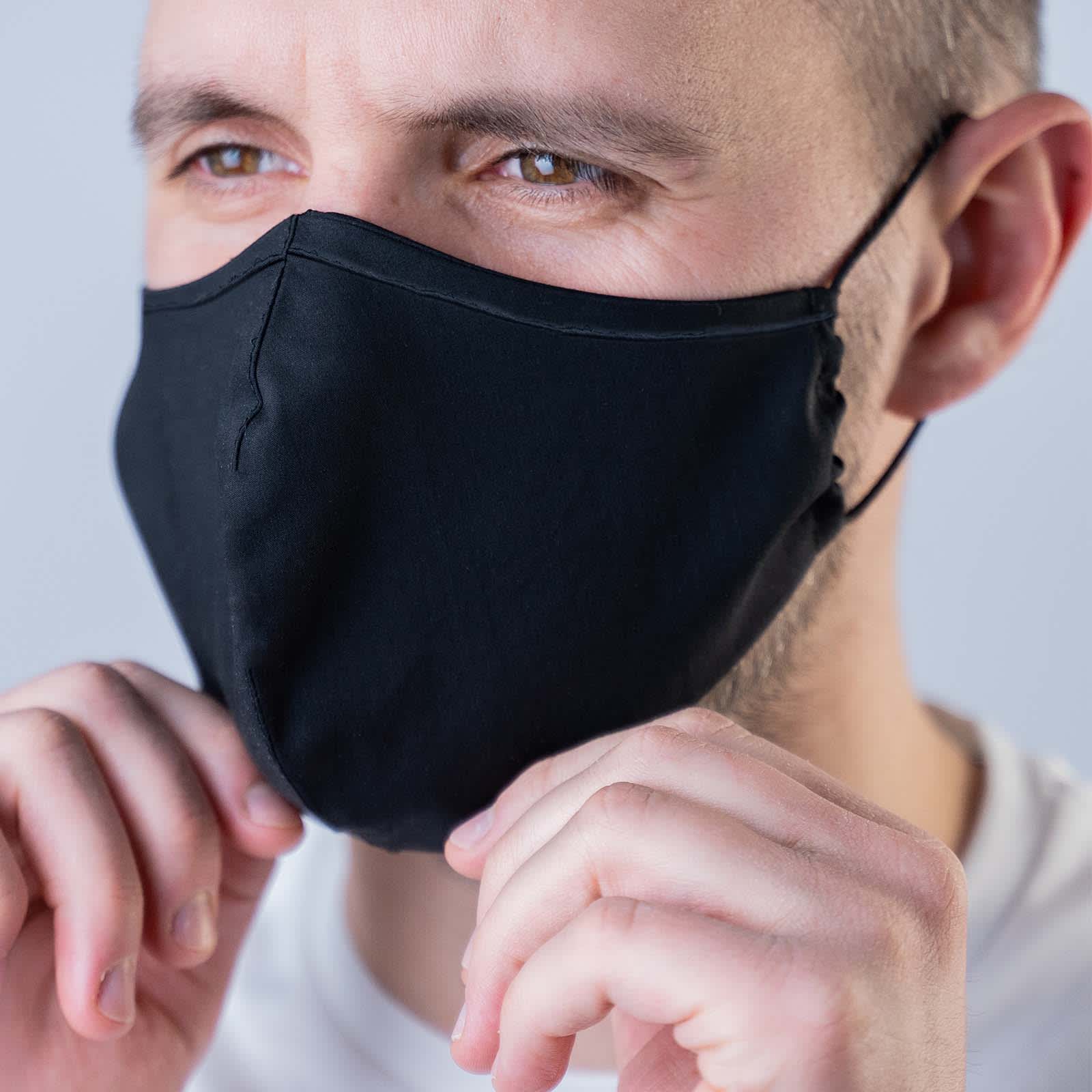A Deluxe Face Mask in black worn by a person, featuring a fitted design.
