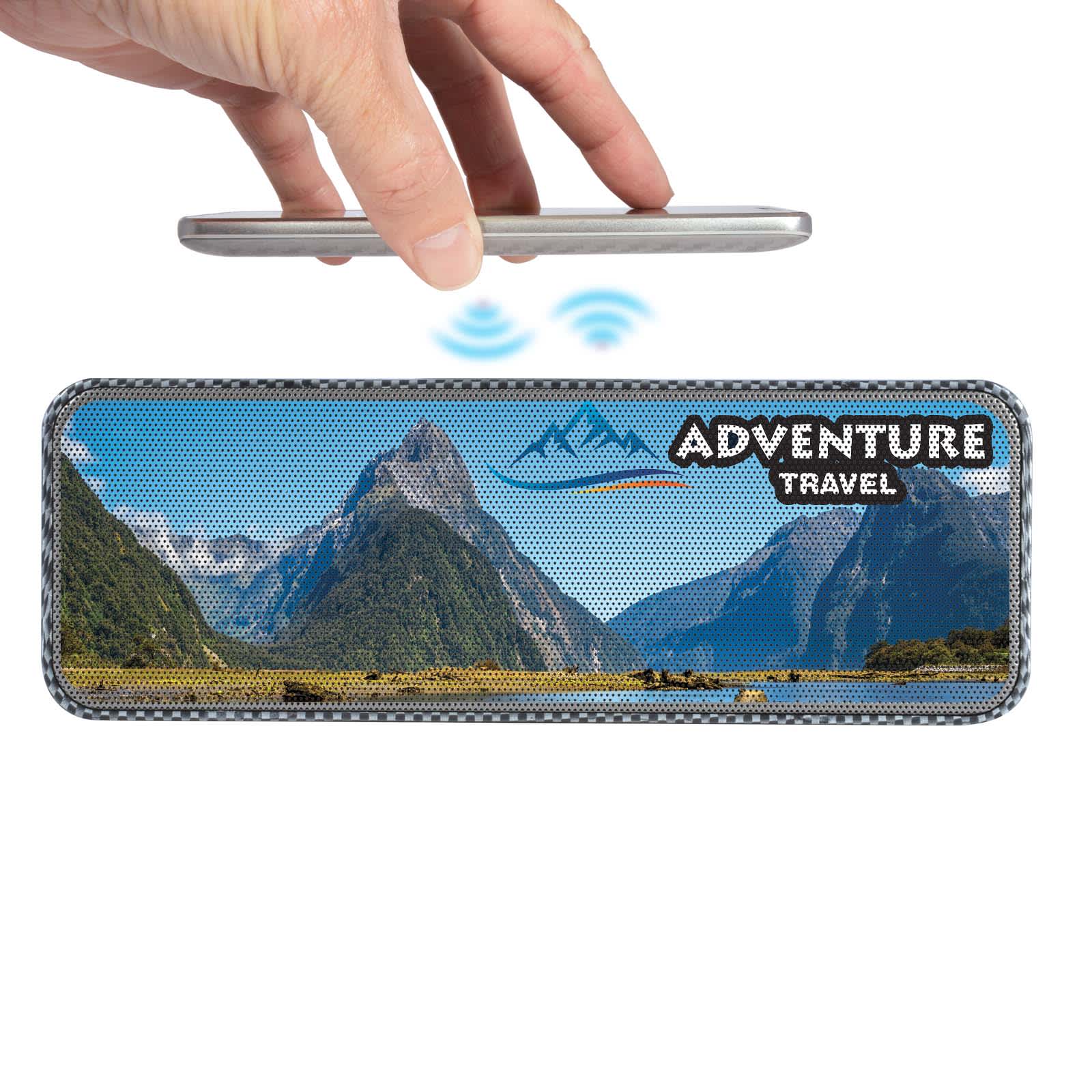 A hand holds a smartphone above a rectangular speaker with a scenic landscape and branding. The product is grey and black.