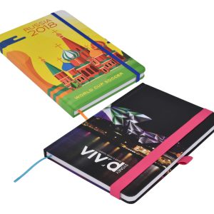 A vibrant, full-colour A5 notebook featuring a design related to Russia 2018 and another with a cityscape, both with elastic bands.