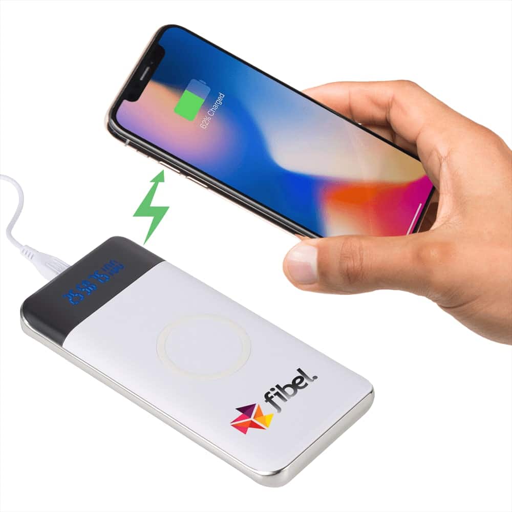 A white wireless power bank with a display and logo, shown charging a smartphone.