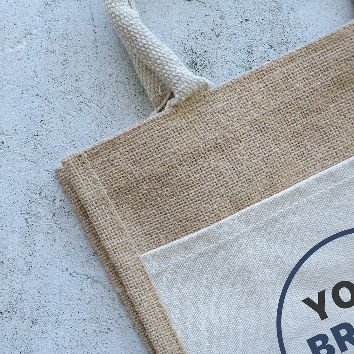 A jute tote bag featuring a natural beige colour with a cream panel and a decorative logo.