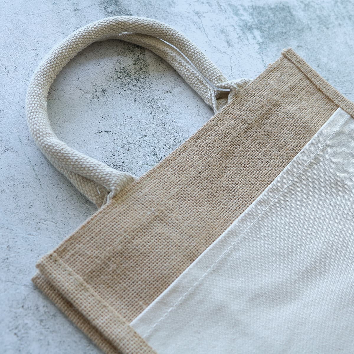 A jute tote bag featuring a natural and cream colour scheme with sturdy handles and a simple design.