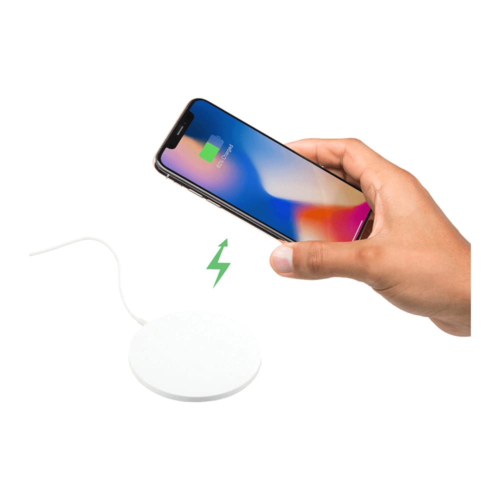 A hand holds a smartphone above a round, white wireless charging pad, with a charging symbol displayed.